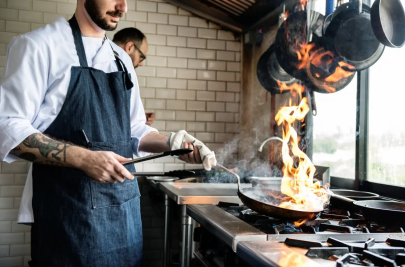 gaz ziemny prosto z rynku elastycznie, kucharz w kuchni restauracyjnej z patelnią nad kuchenką gazową