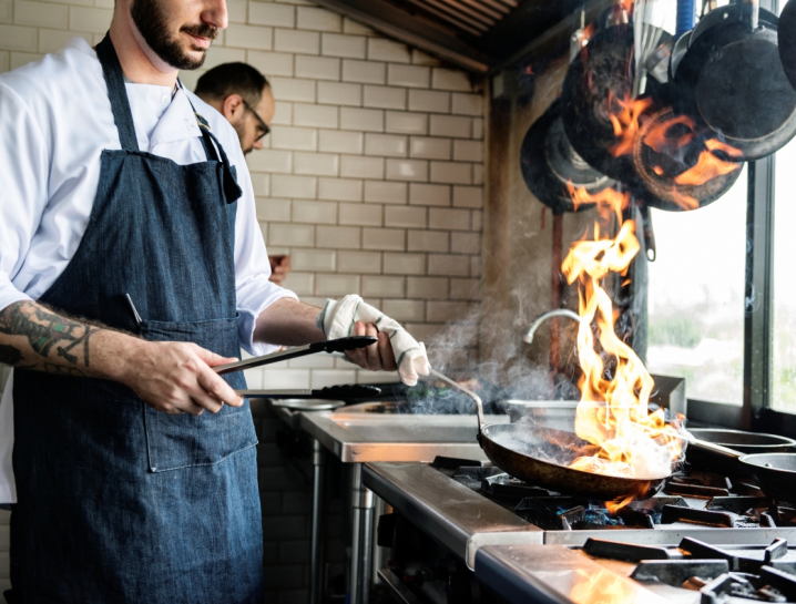 gaz ziemny prosto z rynku elastycznie, kucharz w kuchni restauaracyjnej z patelnią nad kuchenką gazową
