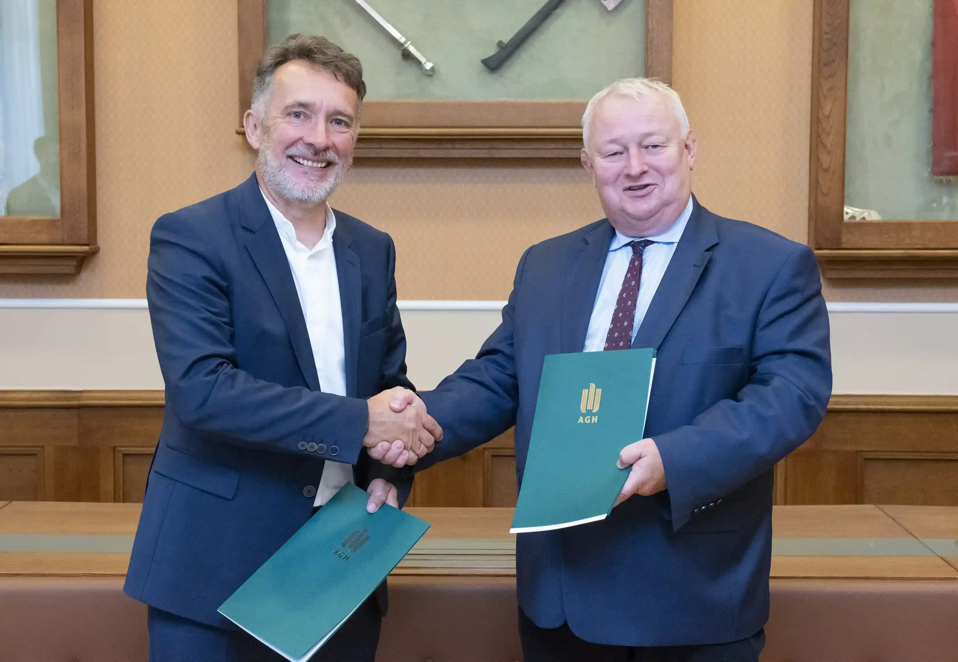 zdjęcie z podpisania współpracy z AGH, prof. dr hab. inż. Rafał Wiśniowski – Prorektor AGH ds. Współpracy i Krzysztof Noga – Prezes Zarządu Elenger Polska podają sobie dłonie trzymając dokumenty porozumienia