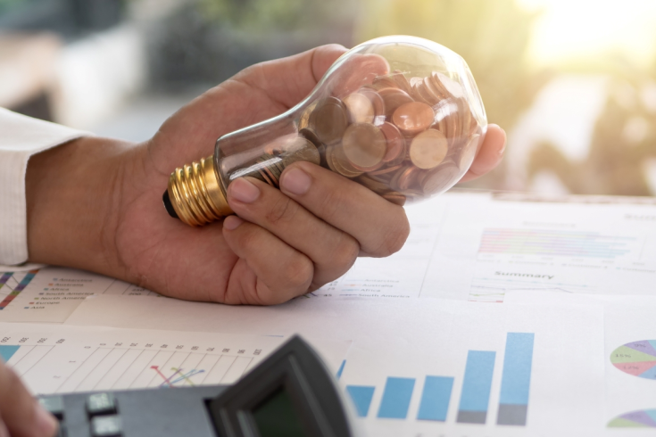 Mężczyzna trzymający żarówkę wypełnioną monetami