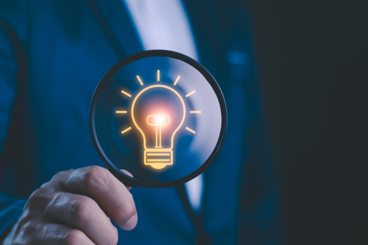 Mężczyzna trzyma lupę z ikoną żarówki