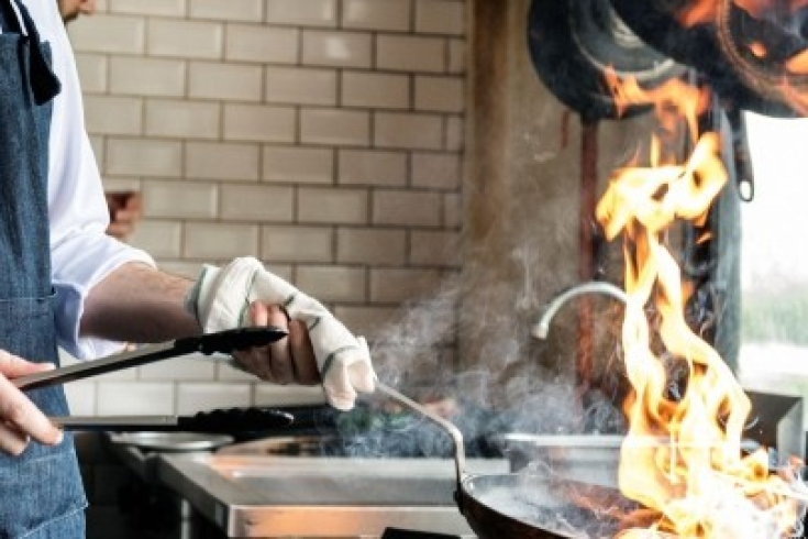 zdjęcia kucharza z patelnią nad palnikiem gazowym smażącego w restauracji